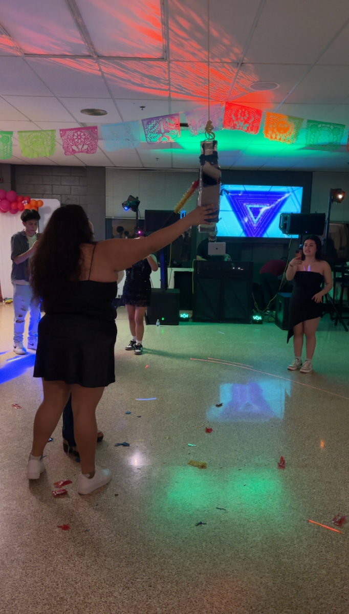Students swing at a piñata full of candy