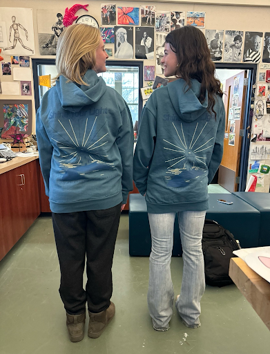 Whitney Bird (left) and Samantha Walsh (right) wearing the blue sweatshirt design